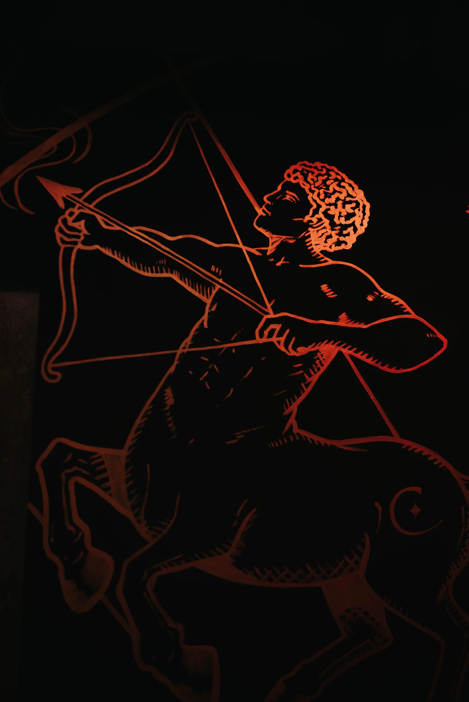 Sagitario grabado en la pared, iluminado en rojo